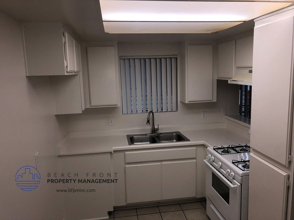 an empty kitchen with white cabinets and a sink