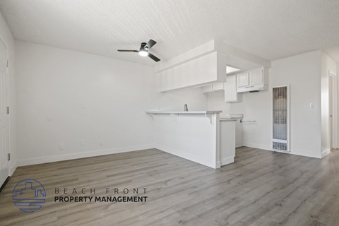 A spacious, empty room with a ceiling fan and a logo for Beach Front Property Management.