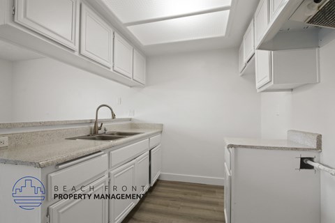 A kitchen with white cabinets and a marble countertop.