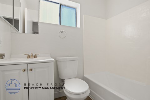 A white toilet sits next to a bathtub in a bathroom.