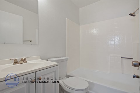 A white bathroom with a toilet, sink, and bathtub.