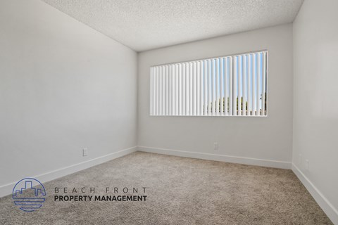A room with a carpeted floor and a window with blinds.