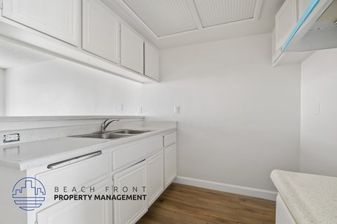 A kitchen with white cabinets and a sink.