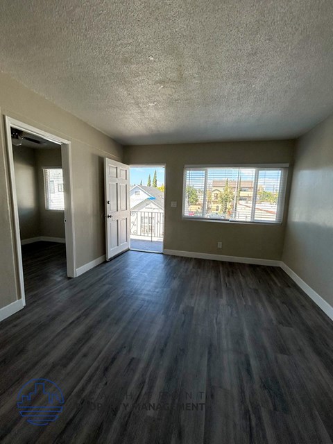 A room with wood flooring and a view of a building outside the window.