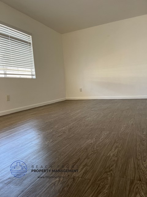 the bedroom of an empty house with wood floors and a window