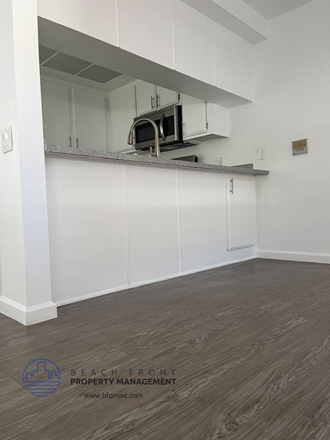 an empty kitchen with white cabinets and a microwave