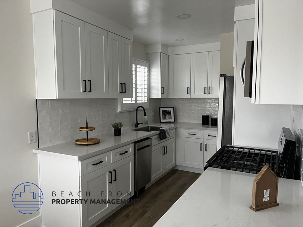 A modern kitchen with white cabinets and a marble countertop.