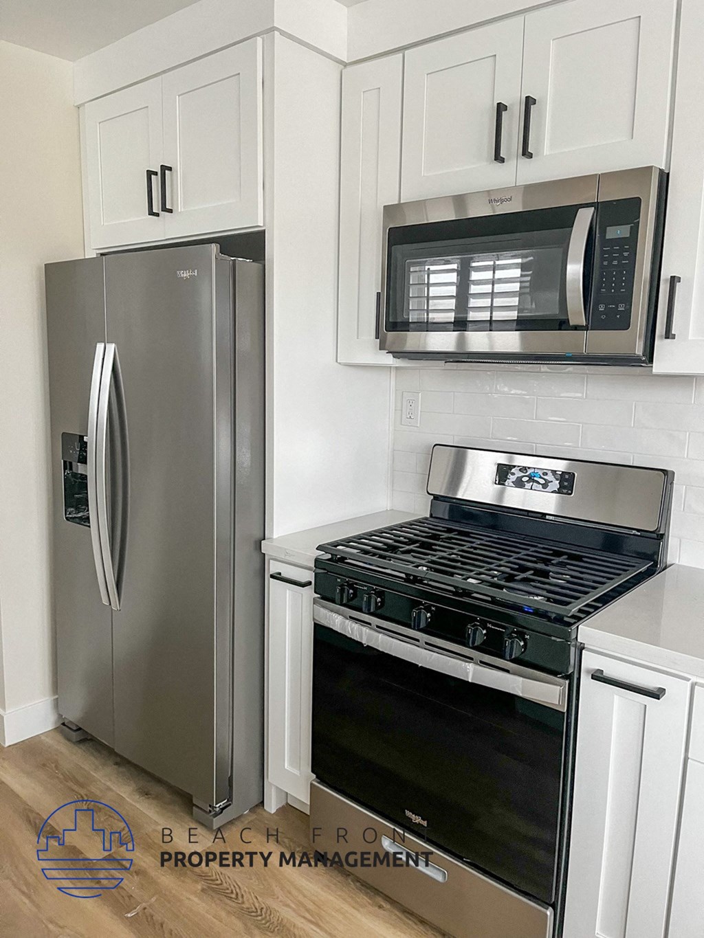 a white kitchen with stainless steel appliances and a refrigerator