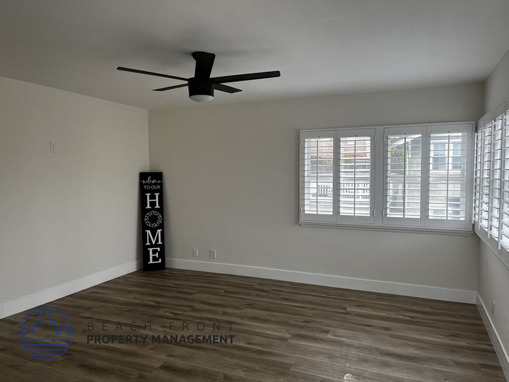 an empty living room with a ceiling fan and window