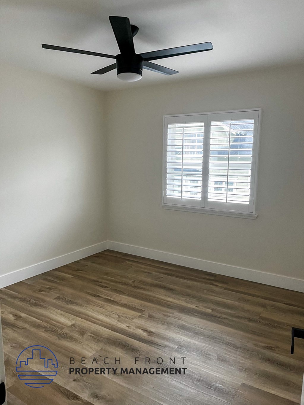 A room with a ceiling fan and wooden flooring.