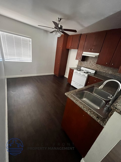 A kitchen with a sink, stove, and fan.