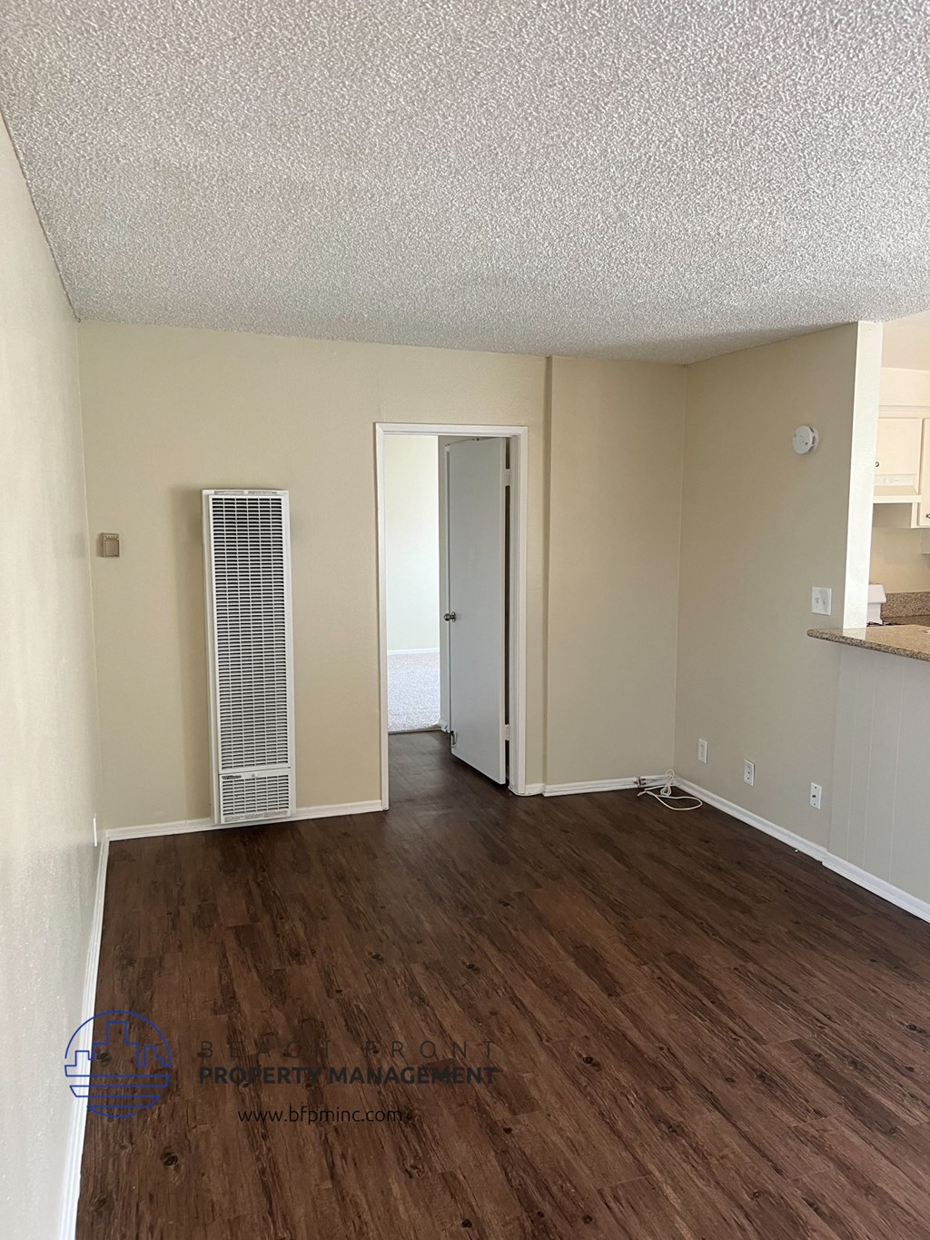 an empty living room with wood flooring and white walls