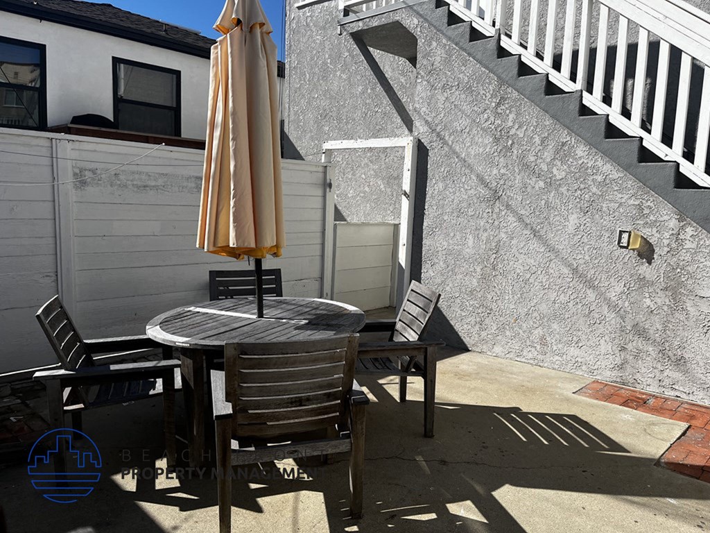 A patio with a table, chairs, and an umbrella.