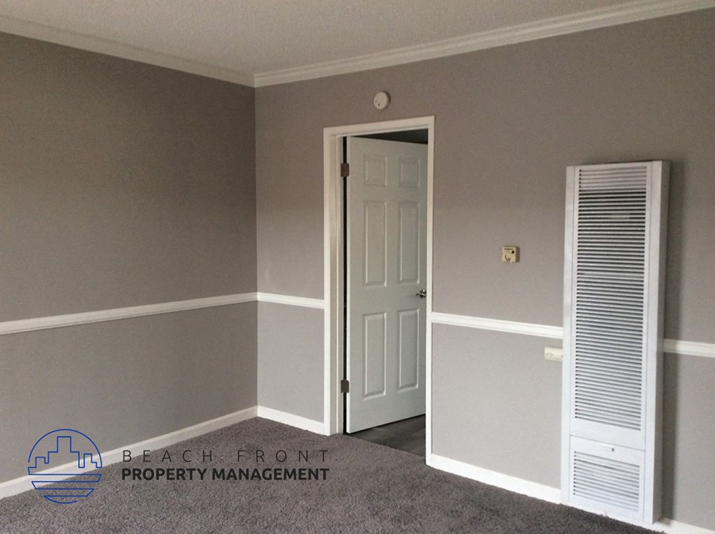 a bedroom with a white door and grey walls and a white closet