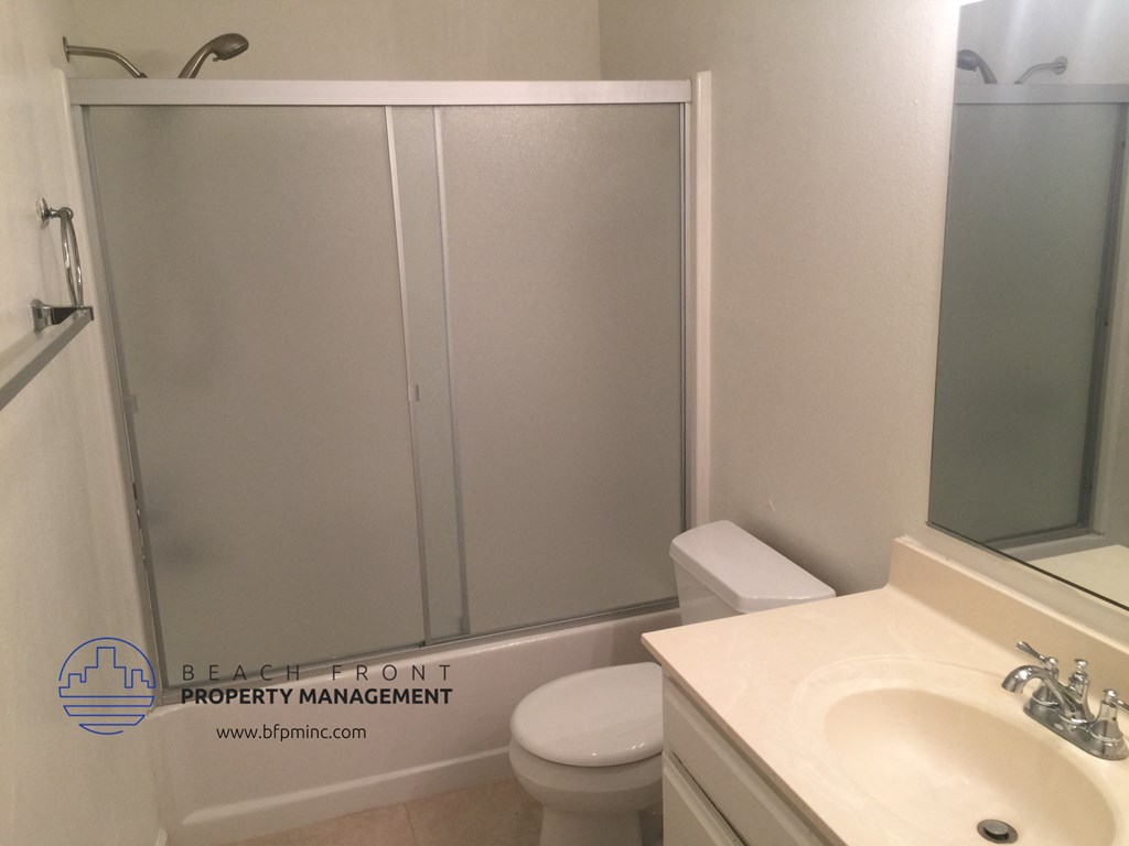 a bathroom with a white sink and toilet and a shower with a sliding glass door