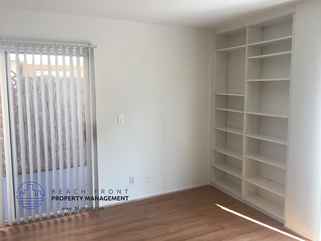 the interior of a bedroom of a house with white walls and a wooden floor