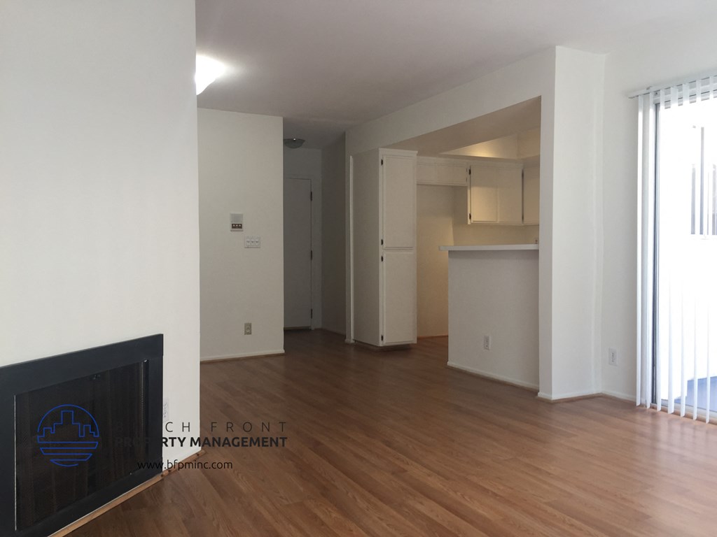 an open living room and kitchen with hardwood floors and white walls