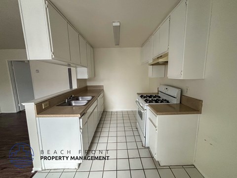 A kitchen with white cabinets and a tiled floor.