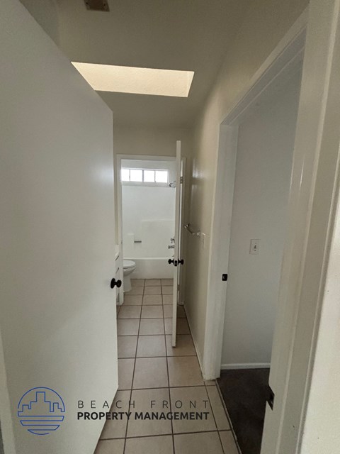 A hallway with tiled floors and white walls.