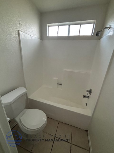 A white toilet sits next to a bathtub in a small bathroom.