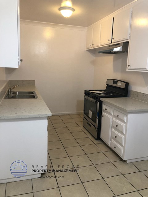 a kitchen with white cabinets and a stove and a sink