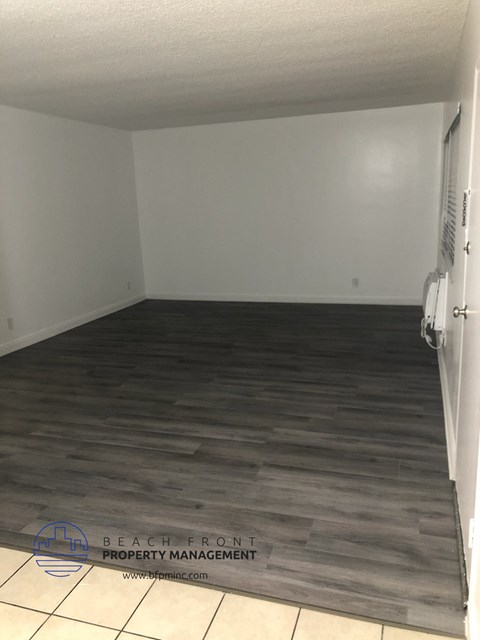 an empty room with wood flooring and a white wall