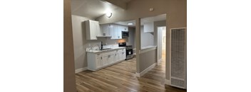 A kitchen with white cabinets and a wooden floor.