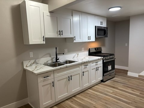 A kitchen with white cabinets and a marble countertop.