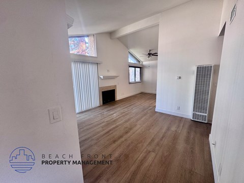 A spacious room with wooden flooring and a ceiling fan.
