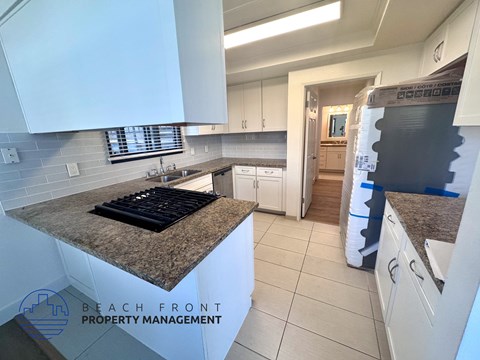 A kitchen with granite countertops and white cabinets is for sale.