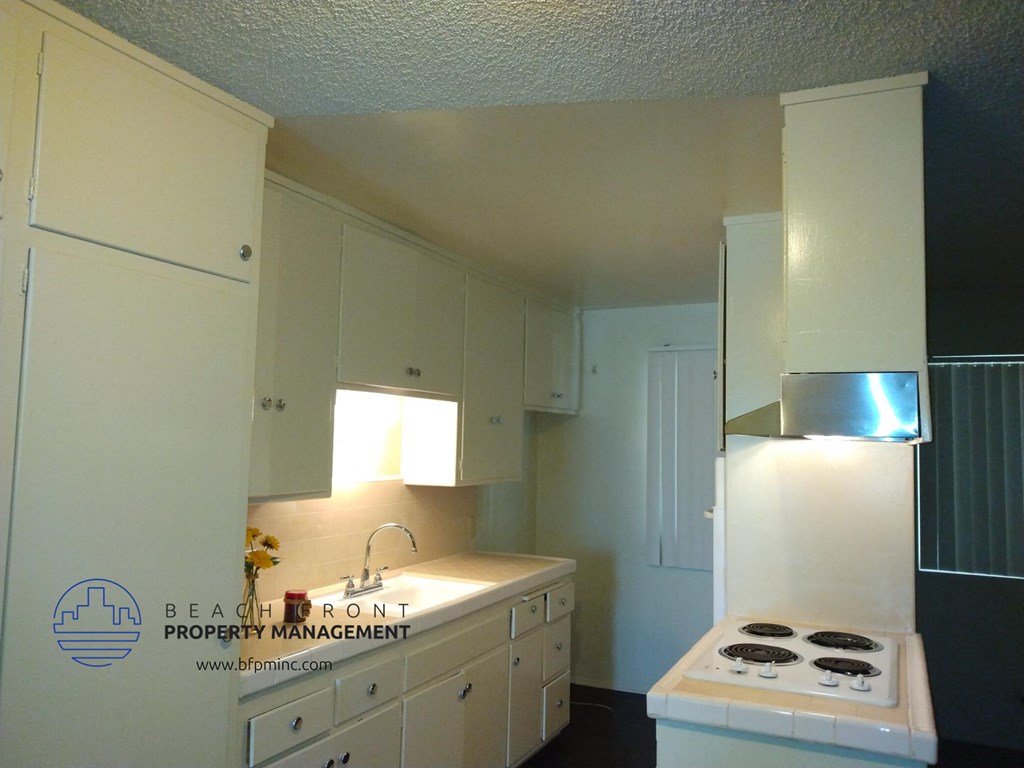 a kitchen with white cabinets and a stove and a sink