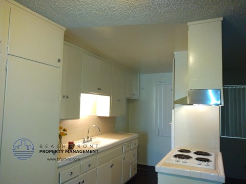 a kitchen with white cabinets and a stove and a sink
