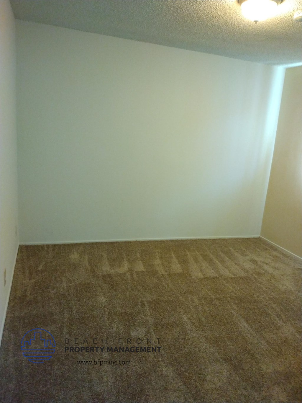 an empty room with a carpeted floor and a white wall