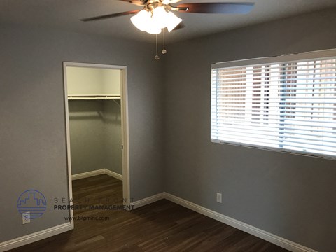 the bedroom of a house with a closet and a ceiling fan