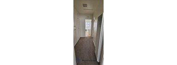A hallway with a carpeted floor and white walls.