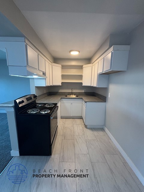 A kitchen with a black stove top oven and white cabinets.