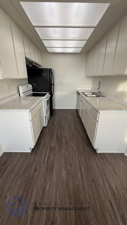 A kitchen with white cabinets and a black fridge.