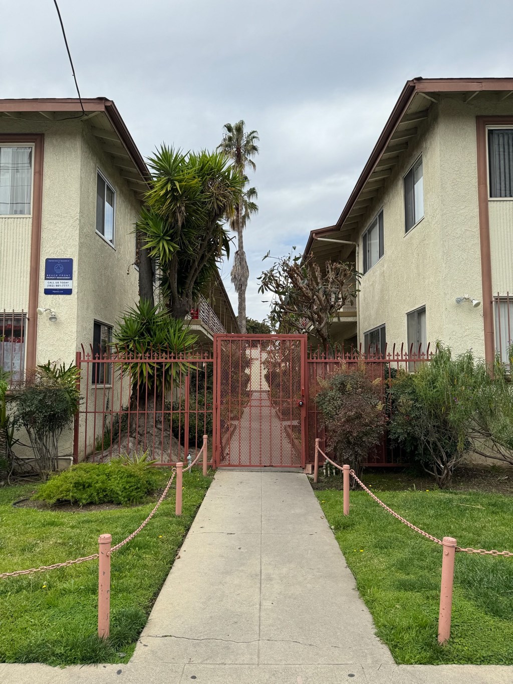 a pathway between two houses with a red gate