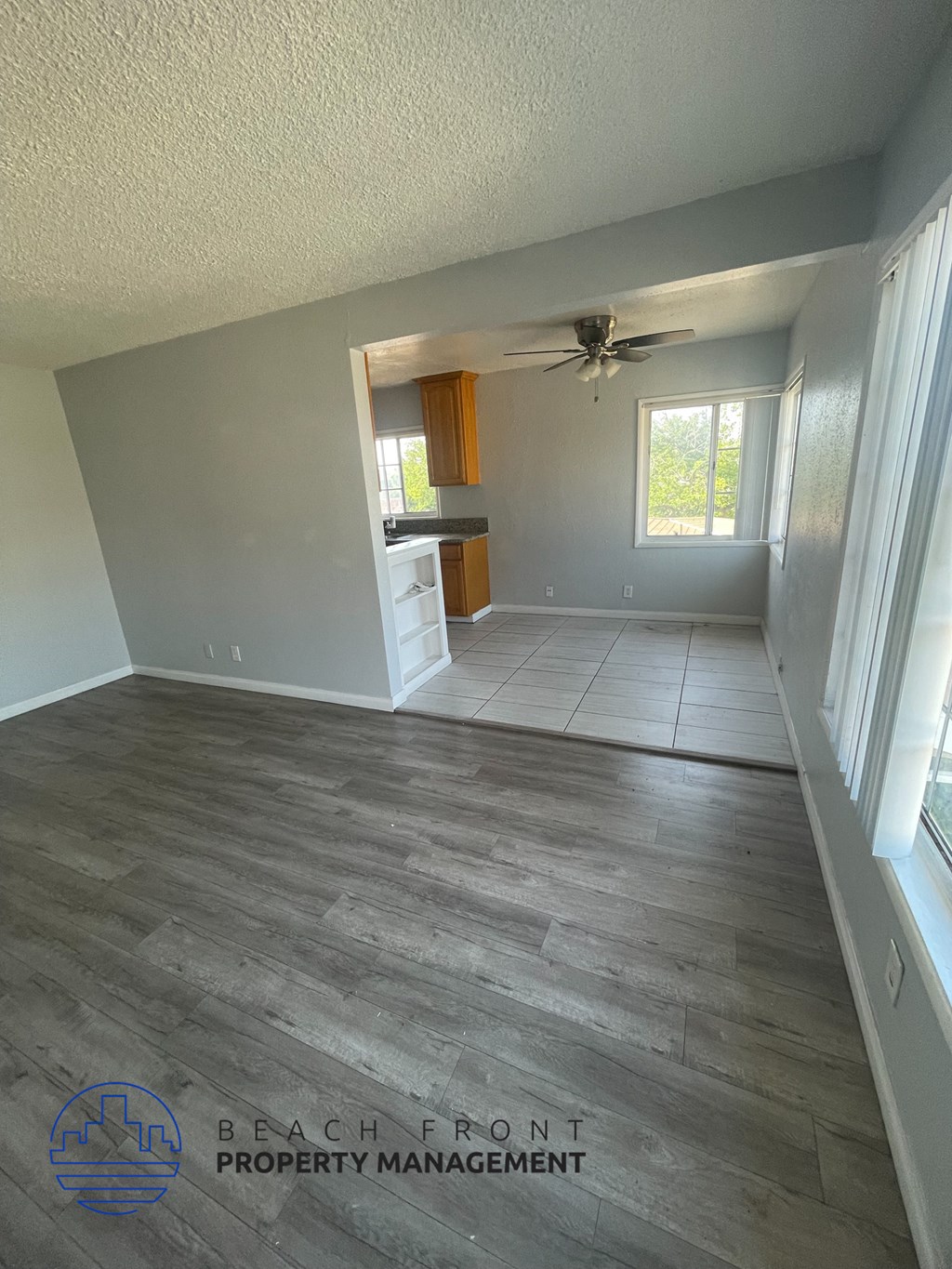 an empty living room with wood flooring and a ceiling fan