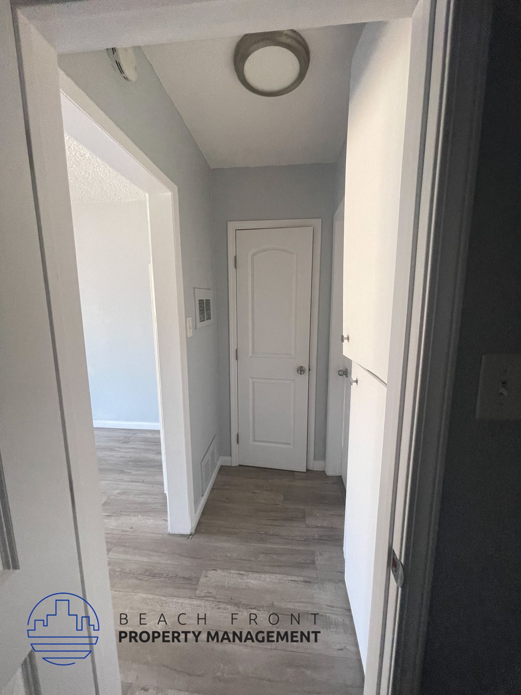 a small hallway with a white door and a hallway with grey walls and a closet
