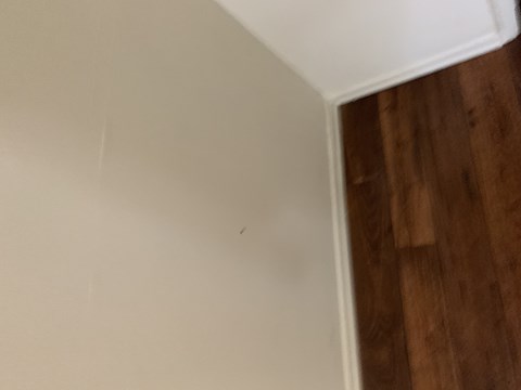 the corner of a wall with a wooden floor and a white wall with white paint