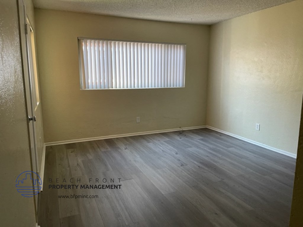 the living room of an empty room with wooden floors and a window