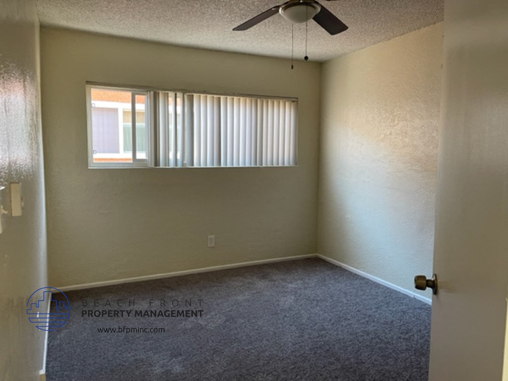 an empty room with a window and a ceiling fan