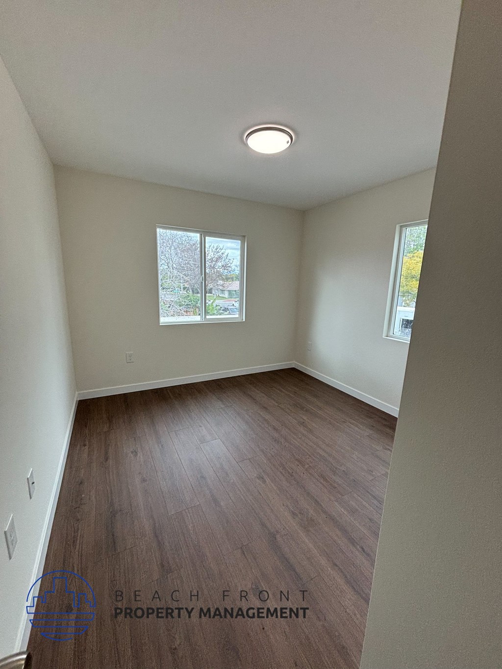 A room with wooden flooring and a window showing trees outside.