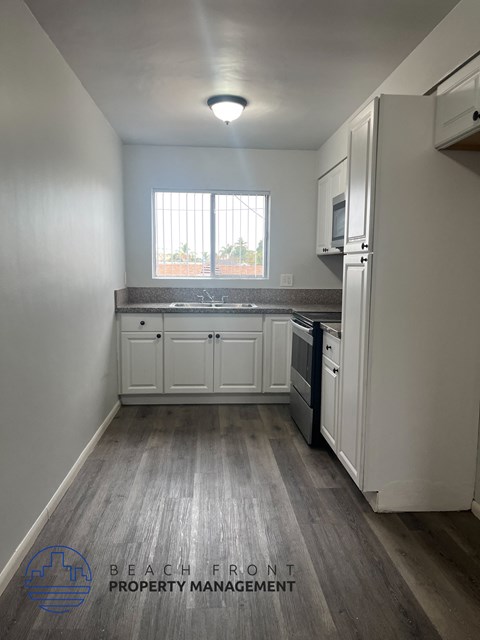 A kitchen with white cabinets and a wooden floor.