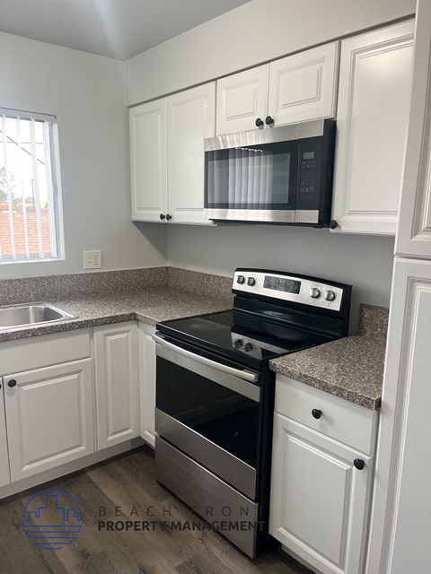 A kitchen with a black stove top oven and white cabinets.