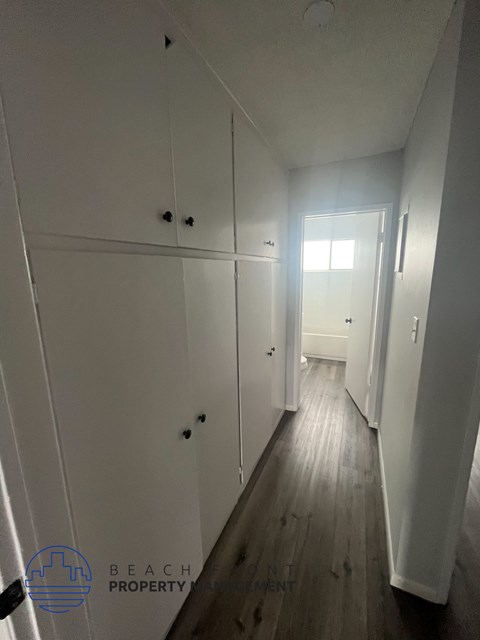 A long hallway with white walls and wood floors.