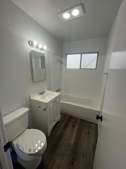 A white bathroom with a toilet, sink, and mirror.