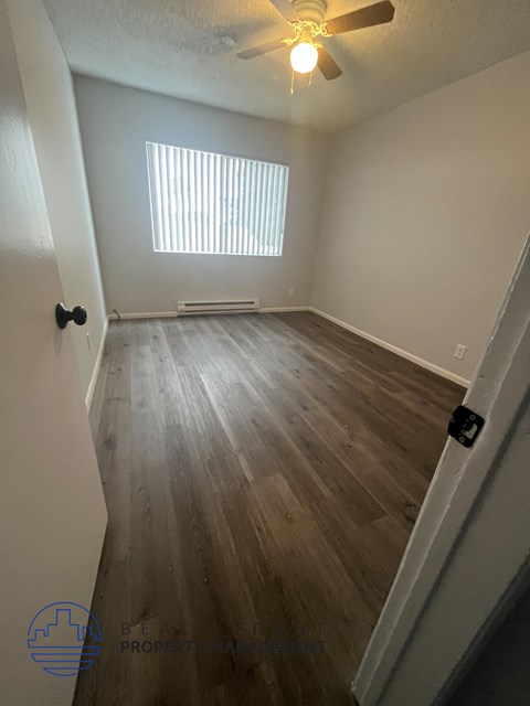 A room with a ceiling fan and wooden flooring.