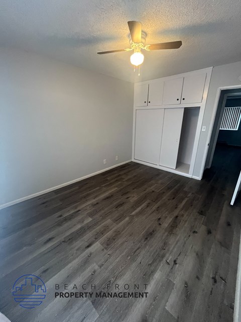 A room with a ceiling fan and wooden flooring.